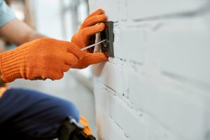 Male electrician hands repairing electrical wall socket