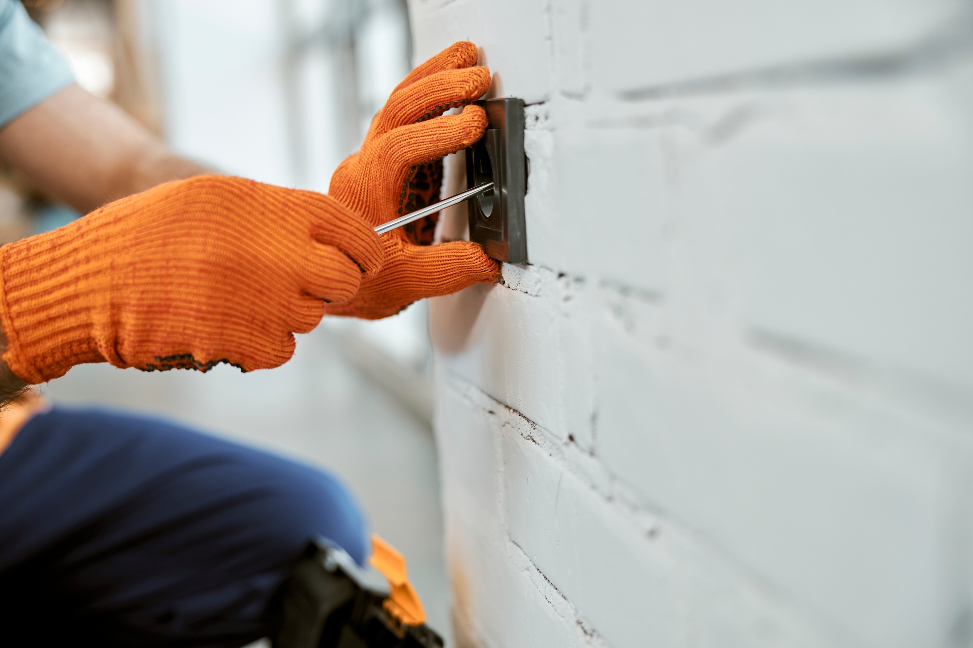 Male electrician hands repairing electrical wall socket